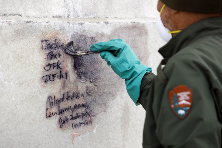 A U.S. Park Service employee works to clean graffiti off the Washington Monument on Tuesday in Washington.