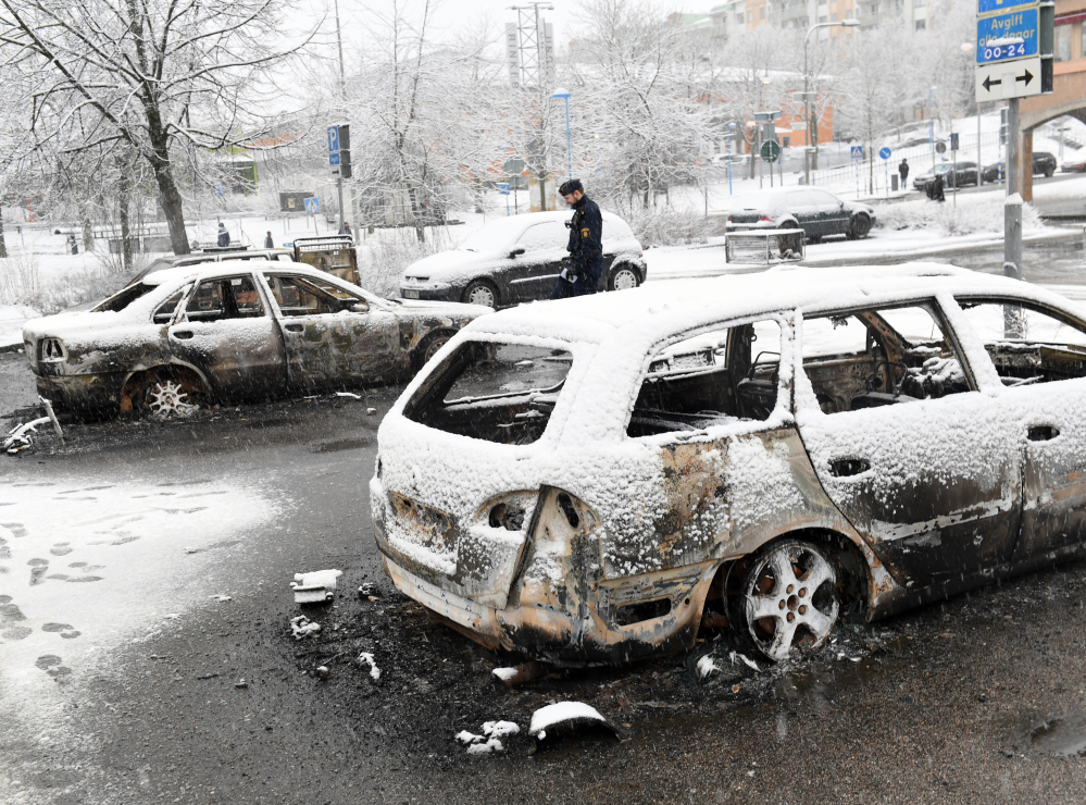 A police officer investigates a burned out car in Rinkeby, outside Stockholm, on Monday. While the country has some friction, it's hardly an extremist breeding ground.