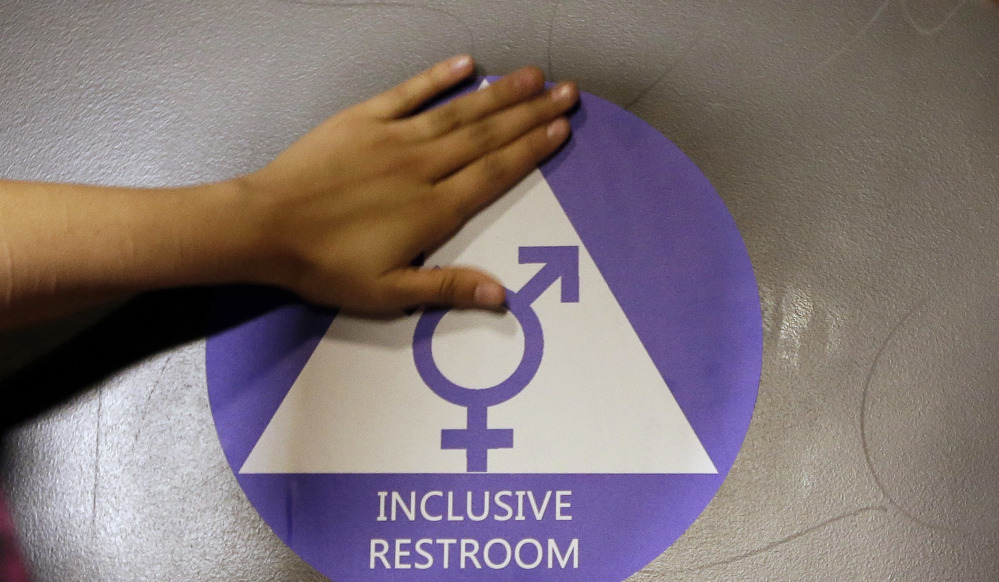 A new sticker is placed on the door at the ceremonial opening of a gender-neutral bathroom at Nathan Hale High School in Seattle last May. A government official says the Trump administration will revoke guidelines that say transgender students should be allowed to use bathrooms and locker rooms matching their chosen gender identity.