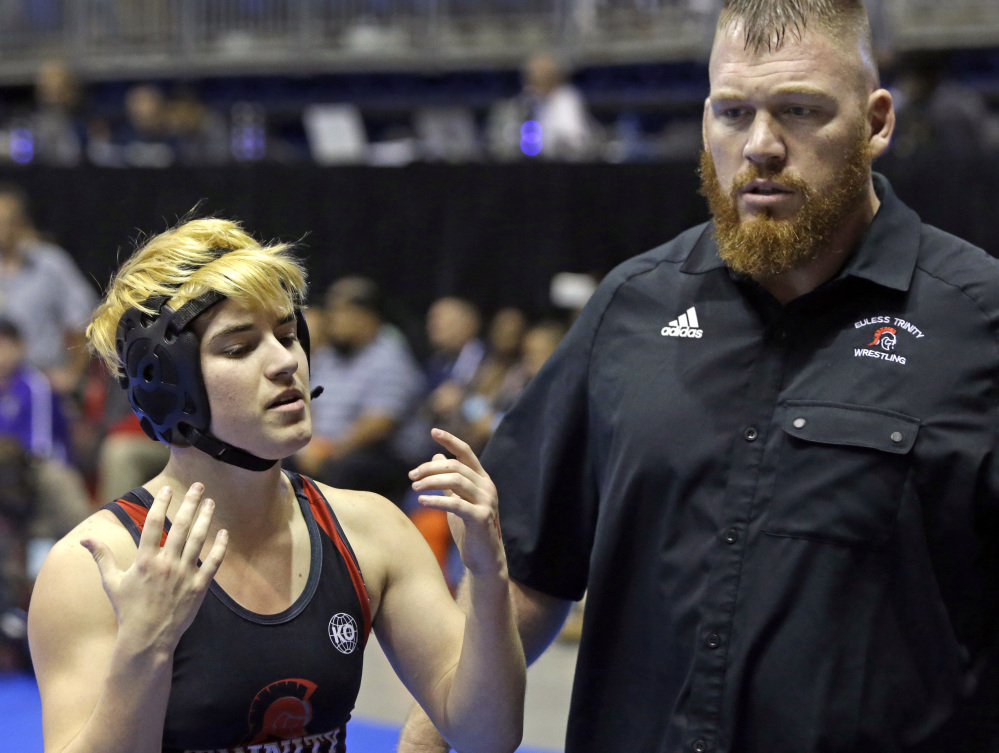 Mack Beggs talks with his coach Travis Clark. Beggs was born female and is transitioning to male. Some say the testosterone treatments Beggs has been taking make him too strong to wrestle fairly with girls.
