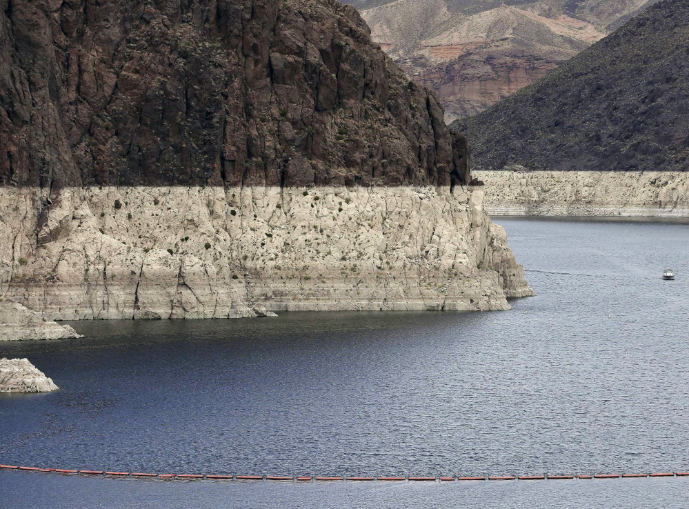 A "bathtub ring" marks the high water mark as a recreational boat approaches Hoover Dam along Black Canyon on Lake Mead, the largest Colorado River reservoir, in 2013.