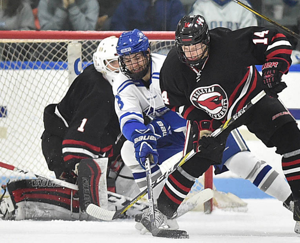 Colby's Devin Albert, center, battles for the puck with Wesleyan's Spencer Fox, right, in front of Cardinals goalie Dawson Sprigings on Saturday during their NESCAC quarterfinal at Waterville. Wesleyan won 5-4.