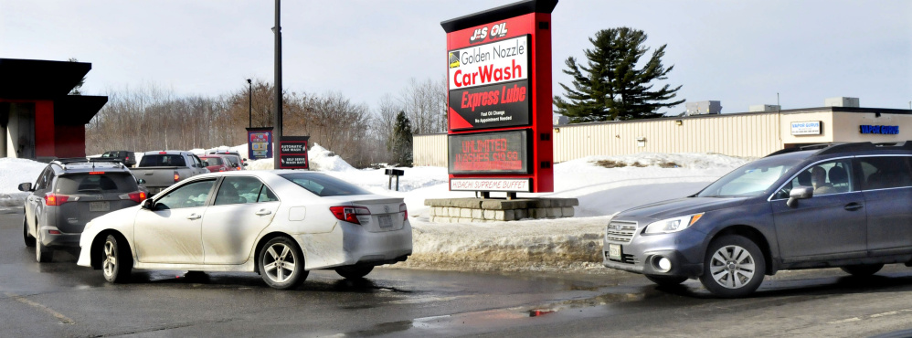 Vehicles idle in a line on Kennedy Memorial Drive in Waterville to enter the J&S Oil car wash on Wednesday, a day after police warned motorists not to park along the road while waiting in line for the car wash.