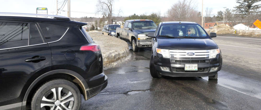 Vehicles on Kennedy Memorial Drive in Waterville wait to enter the J&S Oil car wash on Wednesday.
