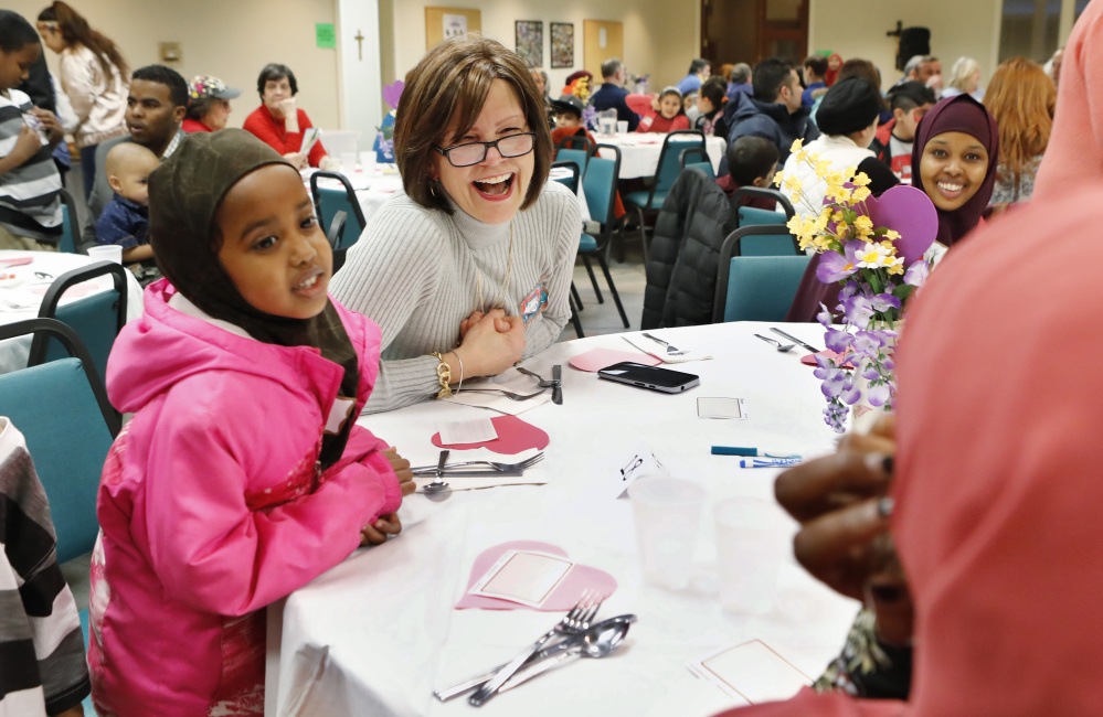 Kelly Dell'Aquila, center, Habso Ali, 8, left, and others interact during the Building Bridges dinner at Saint Maximilian Kolbe church in Scarborough. "We need more of this," said Zoe Sahloul of Westbrook. "Whenever we have the chance, we need to come together."