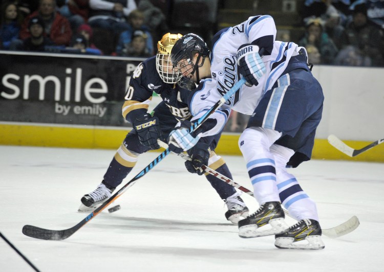 Maine forward Peter Housakos, 24, battles Notre Dame's Anders Bjork for a loose puck in February.
