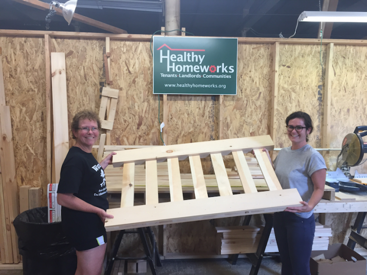 Amy Smith, left, and daughter Allie of Healthy Homeworks move a bed frame part at the nonprofit’s facility in the Pepperell Mill in Lewiston.