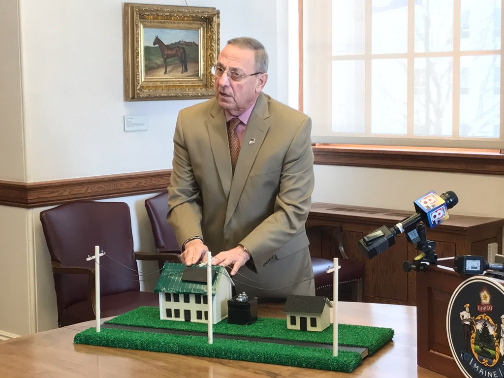 Gov. Paul LePage uses a prop model of two houses to make a point about residential solar energy use on Friday in Augusta.