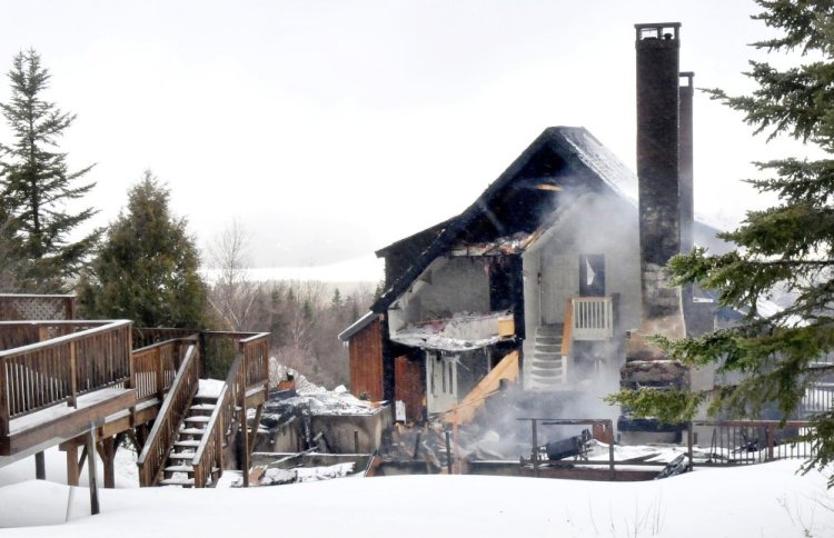 Smoke still rises Wednesday beside a bare chimney from the remains of a Rock Pond condominium destroyed by fire Tuesday night at Saddleback Ski resort in Rangeley. Two adjacent condos were also damaged by the wind-swept fire. 