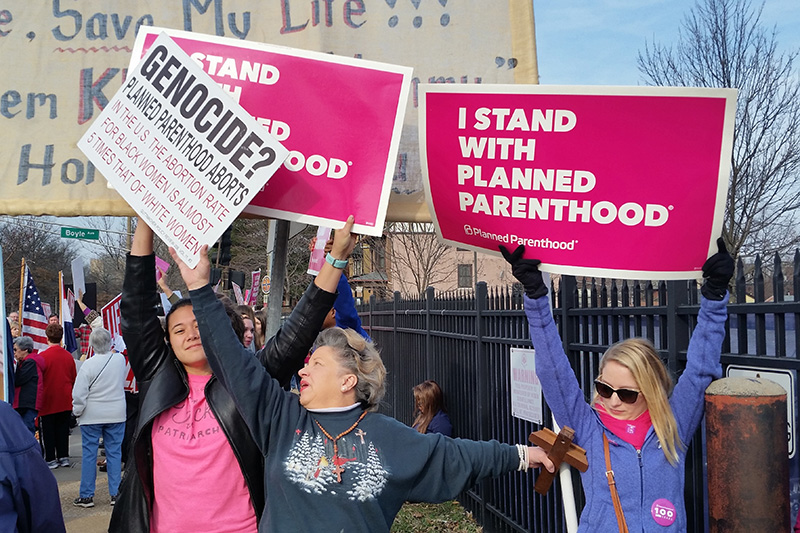 A Planned Parenthood supporter and opponent try to block each other's signs during a protest and counter-protest Saturday  in St. Louis.   