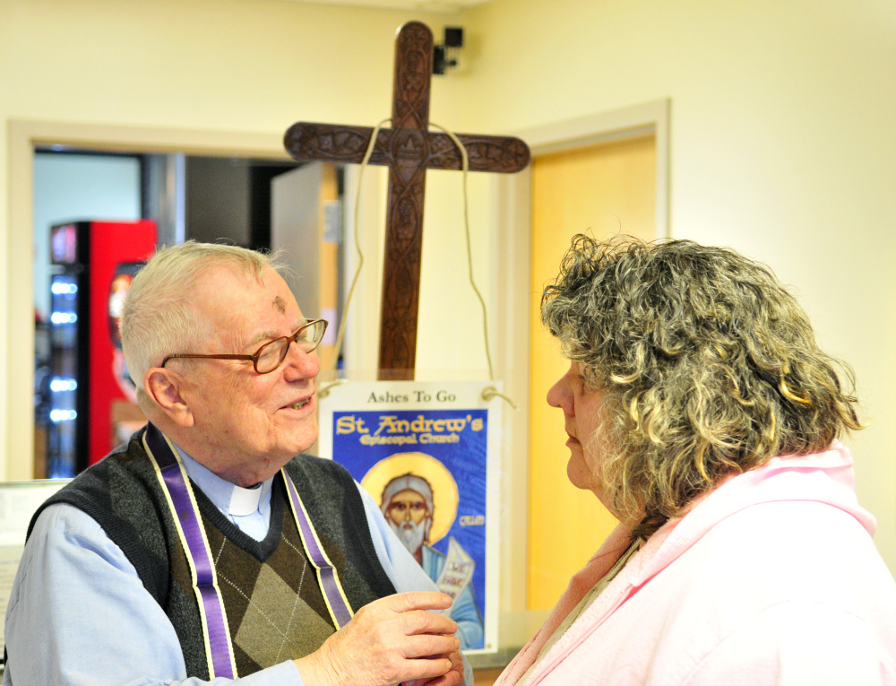 The Rev. James Gill chats with Theresa Edwards before marking a cross with ashes on her forehead Wednesday at the Winthrop Commerce Center.