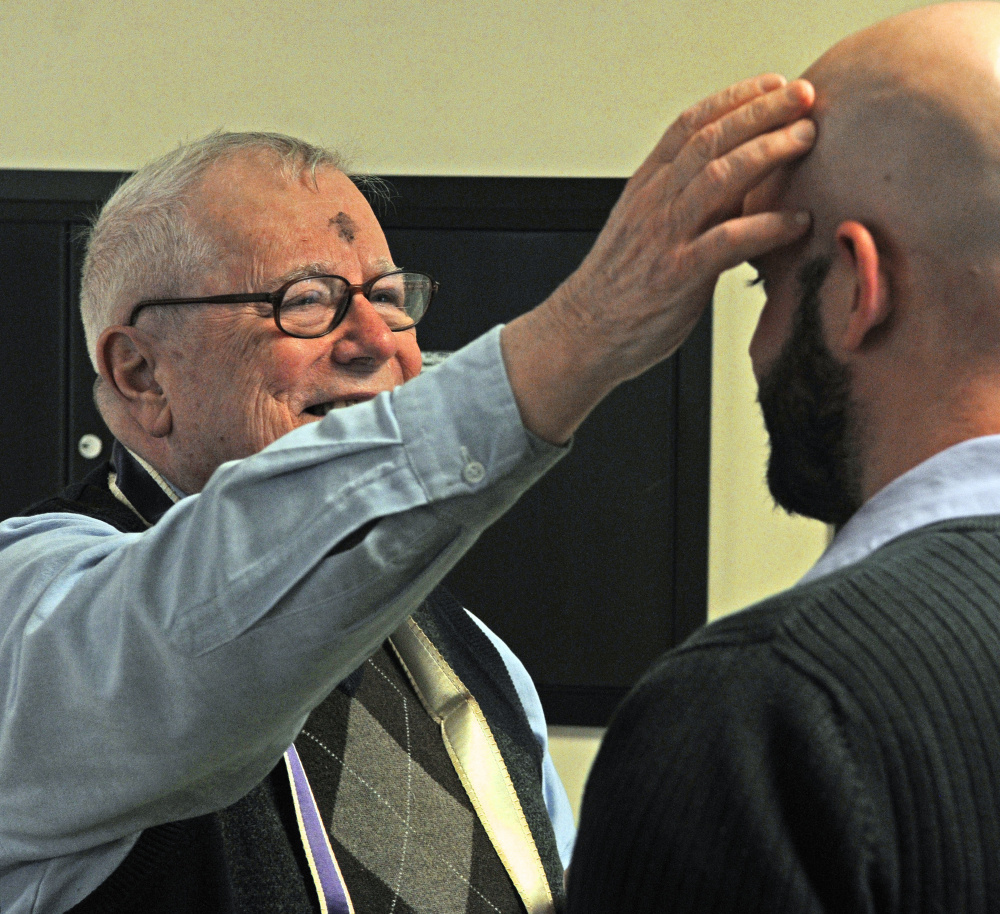 The Rev. James Gill applies ashes to Stephen Farrington's forehead Wednesday at the Winthrop Commerce Center. Gill was taking part in the international Ashes To Go program on Ash Wednesday, the beginning of the Christian season of Lent, which leads up to Easter.