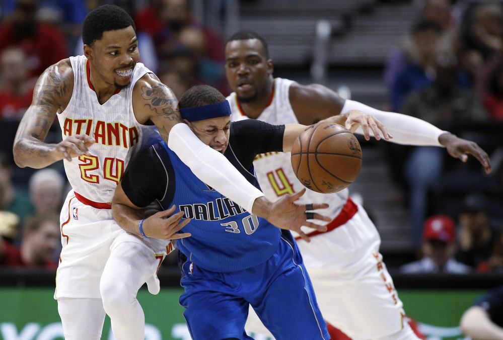 Seth Curry of the Dallas Mavericks, center, attempts to maintain control of the ball Wednesday night while pressured by Kent Bazemore, left, and Paul Millsap of the Atlanta Hawks during the first half of the Hawks' 100-95 victory at home.