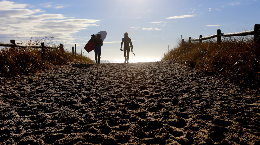 Surfing buddies Stephan Laufer of Germany, left, and Ryan McDermott of Scarborough head toward the water at Scarborough Beach State Park in 2015. About 2.6 million people visited Maine's state parks that year, and attendance neared 2.9 million in 2016.