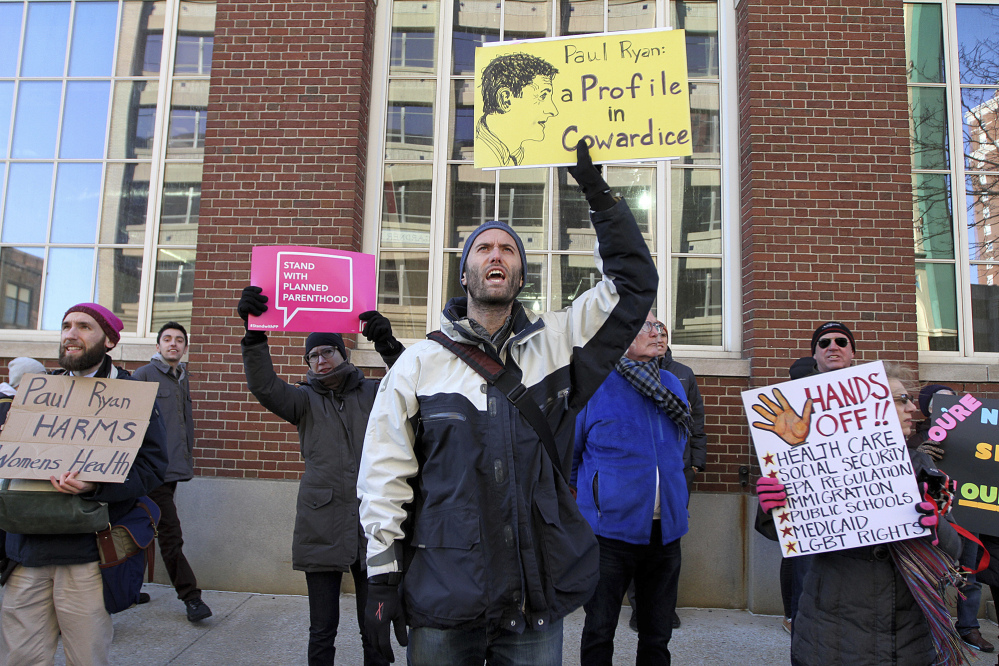 David Stuebe, center, other demonstrators carried signs and chanted "Coward!" in Providence, Rhode Island, on Thursday to protest Republican House Speaker Paul Ryan's appearance and the policies of the Trump administration.
