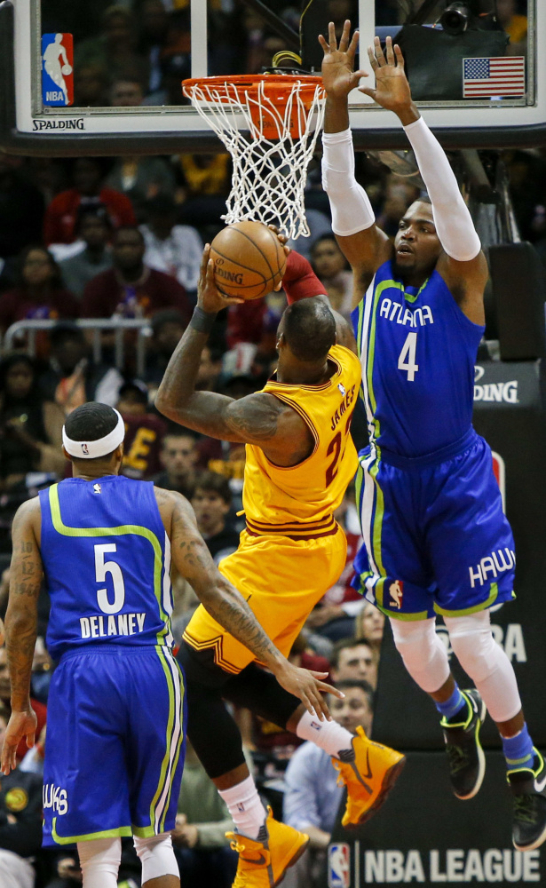 Atlanta forward Paul Millsap, right, leaps to defend against Cleveland's LeBron James during the Cavaliers' 135-130 win on Friday in Atlanta.