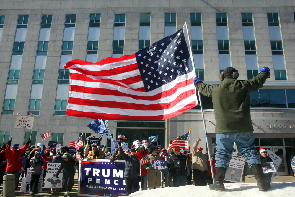 Donnie Heald, of Lincolnville, holds a large American flag Saturday in front of the Burton M. Cross State Office Building as Trump supporters brave below-zero wind chill at a March 4 Trump rally in Augusta. The event was part of a nationwide show of support for President Donald Trump.