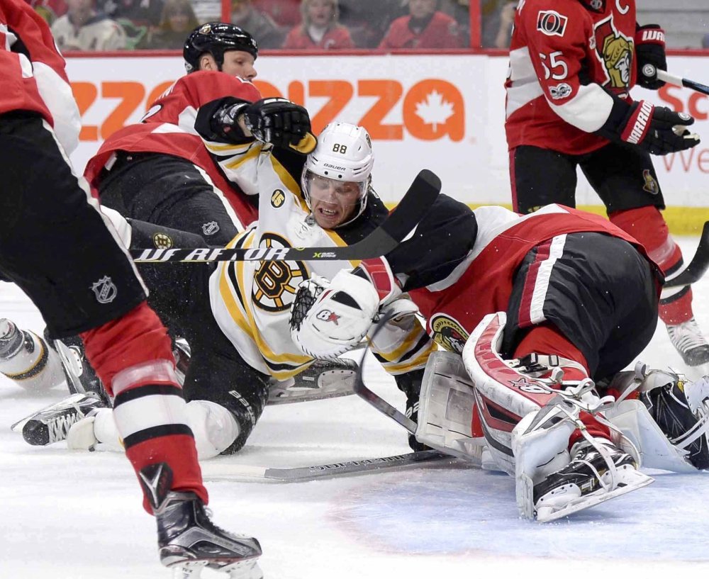 Boston's David Pastrnak, center, crashes into Ottawa goaltender Craig Anderson during the first period of the Bruins' 4-2 loss in Ottawa, Ontario.