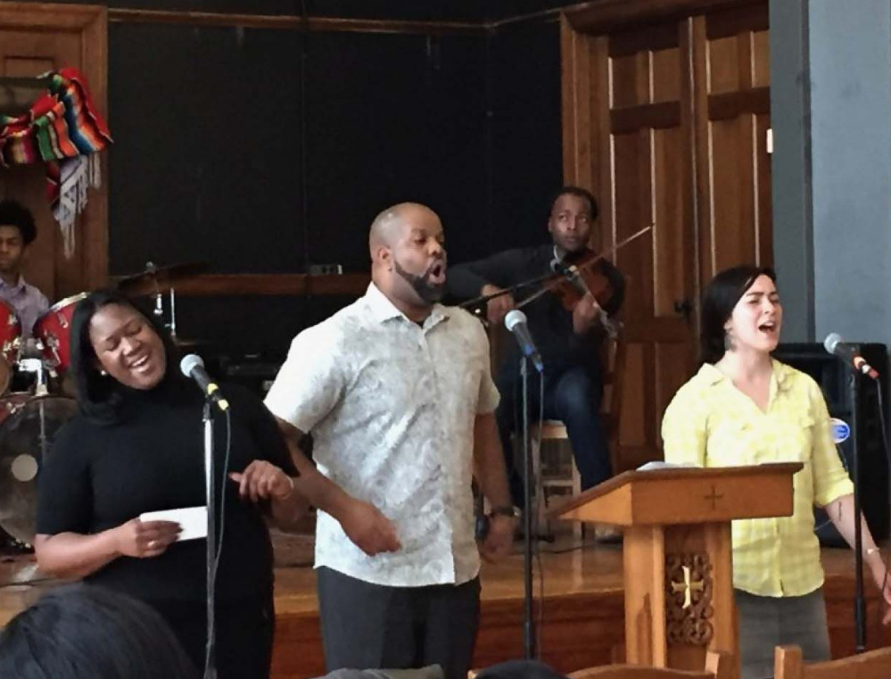 Brittany Wells, left, Pastor Emmett Price and Hilary Davis lead a hymn at Community of Love Christian Fellowship in Boston. Davis says that when she first came to the church, she was inspired by Wells' solo rendition of "I Love You, Lord."