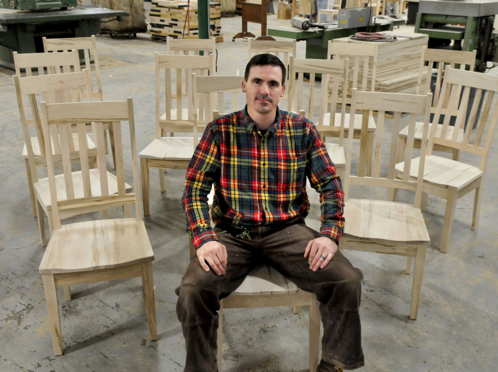 Maine Made Furniture owner Tim Lovett sits in a chair built for Sunday River ski resort at his furniture shop. Lovett closed on the company last fall and opened a location in Wilton. He hopes to do his hiring locally.