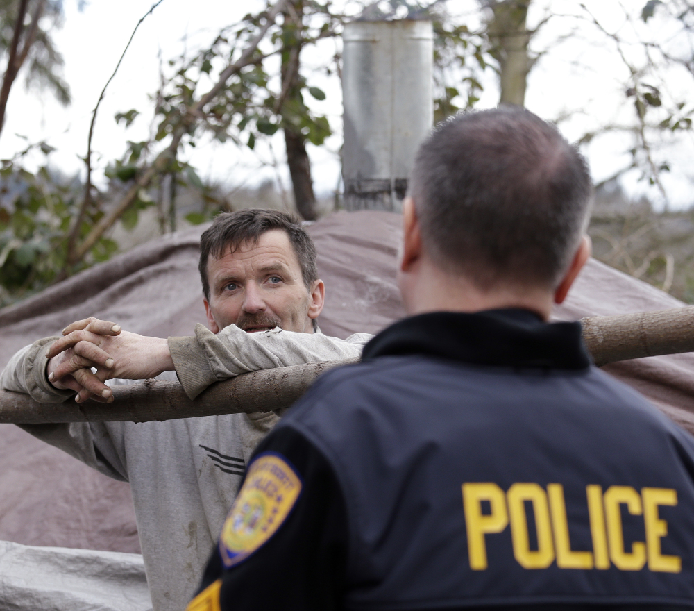A man who lives in a shelter in the woods talks with police Sgt. Mike Braley in Everett, Wash. Braley is part of an outreach effort seeking to connect addicts with treatment.