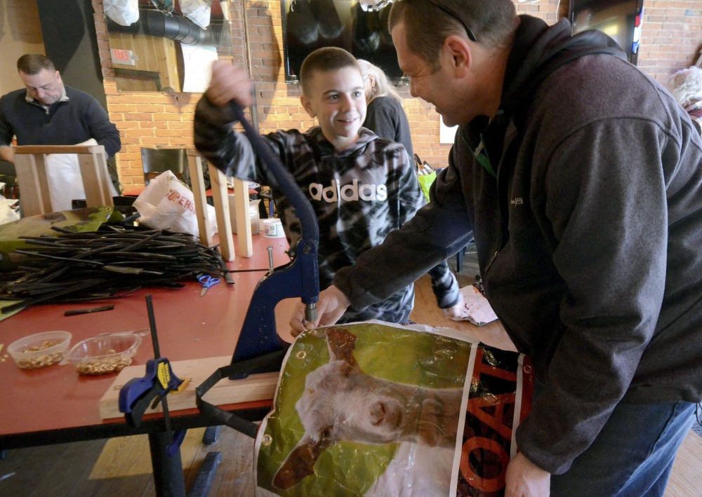 Corey Bishop of Bishop West Real Estate and his nephew Keaton West, 13, make reusable shopping bags at the old Firehouse Cafe in Adams, Mass., on March 5. The town's ban on plastic shopping bags takes effect March 30.