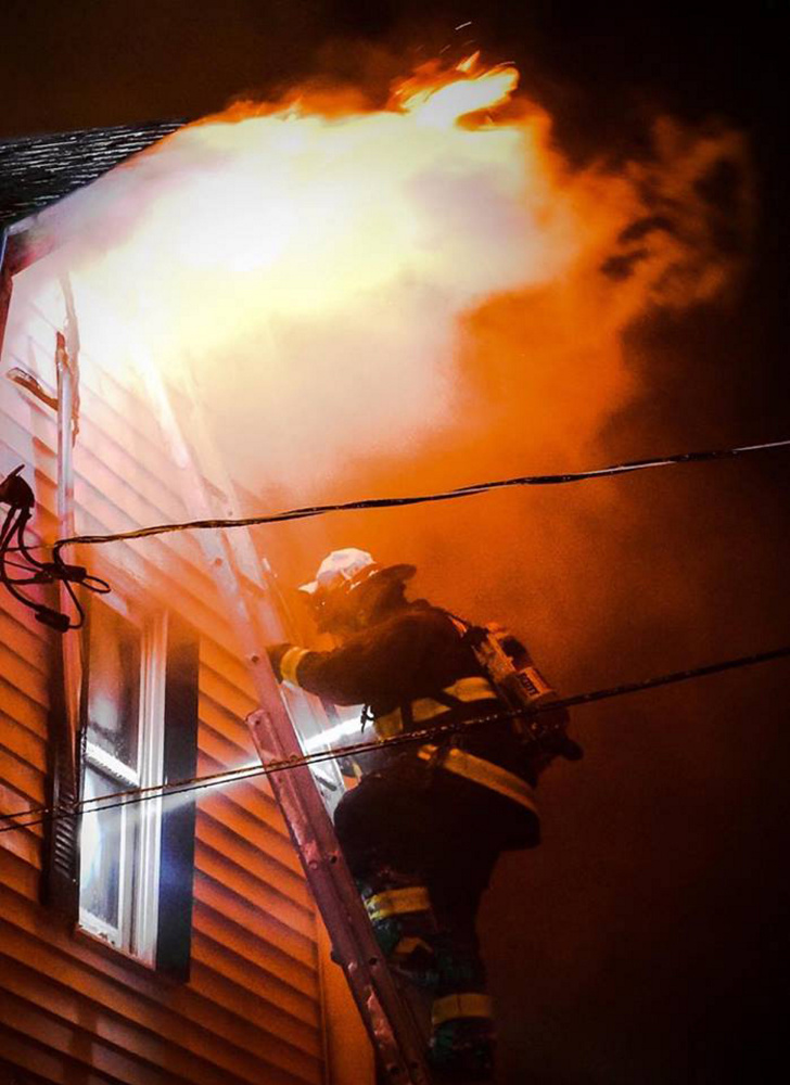 Monmouth firefighter Josh Reny uses a ground ladder to fight a fire that burned a single-family Tuesday night in home in Monmouth.