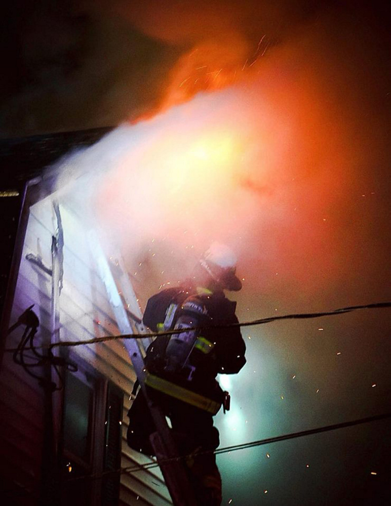 Monmouth firefighter Josh Reny fights the fire that broke out Tuesday night in a home on Route 135 in Monmouth.