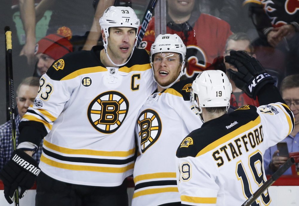 Boston's David Pastrnak, center, celebrates his goal with Zdeno Chara, left, and Drew Stafford in the first period Wednesday night in Calgary.