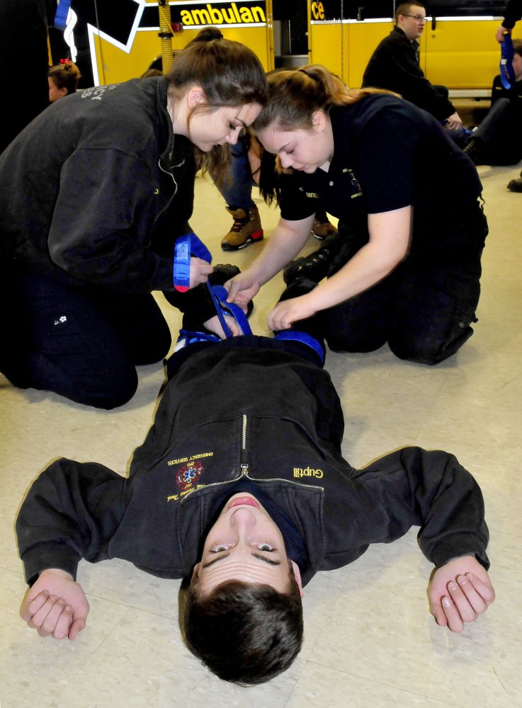 Mid-Maine Technical Center students Ashley Leighton, left, and Emily Melancon apply tourniquets to Hunter Guptill on Thursday during training on stopping bleeding.