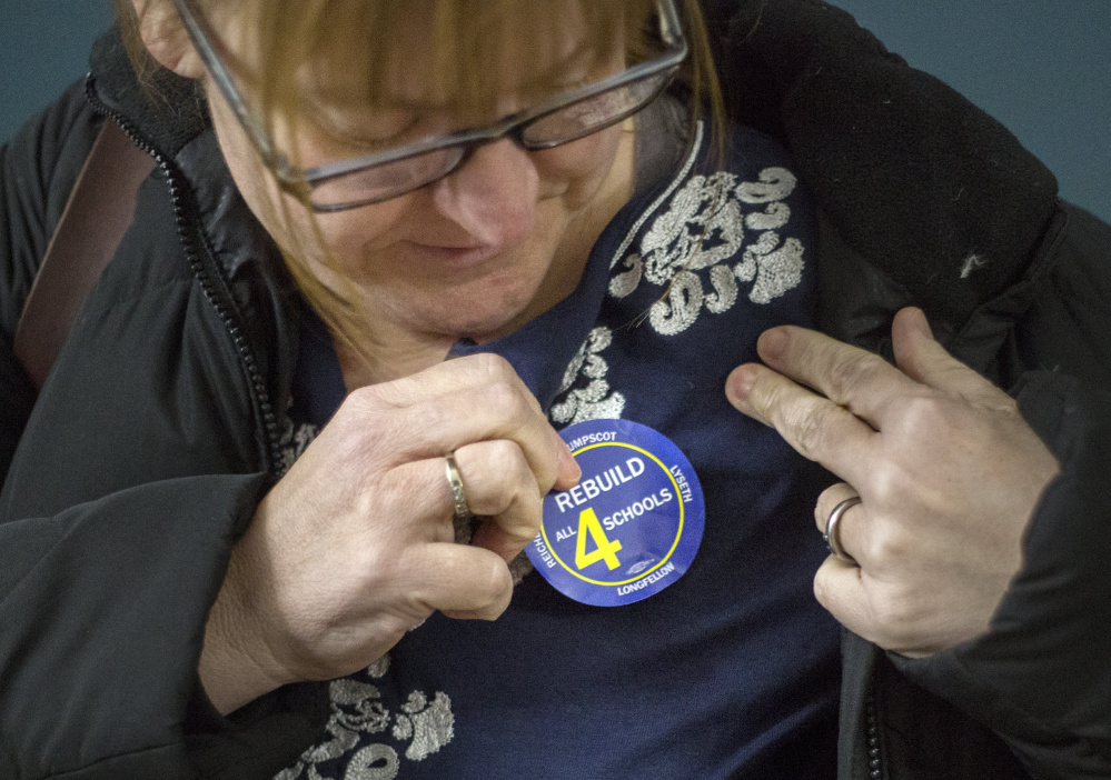 Christine Albert of Portland attaches a sticker before a January public hearing on competing proposals for funding the renovation of four Portland elementary schools. The City Council could vote Monday night on putting a $64 million bond proposal on the ballot.