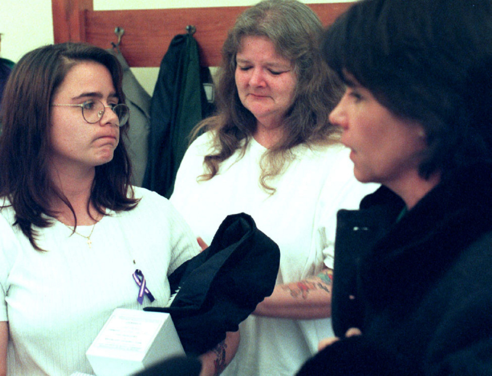 Christy Baker, left, listens to then-Rep. Julie Ann O'Brien, R-Augusta, right, who publicly apologized on behalf of the state for the death of Baker's daughter in 2001. Baker, now named Christy Darling, holds the ashes of Logan Marr. Baker's mother, Katlynn Badger, is in the background.
