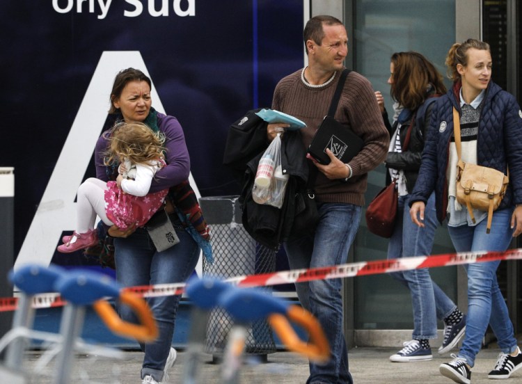 Travelers evacuate Paris' busy Orly Aiport, where French soldiers shot and killed a man who attacked one of their colleagues and tried to steal her rifle Saturday.