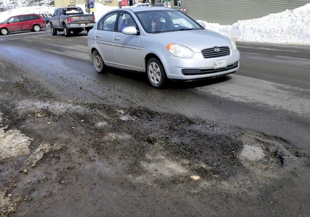 A driver in Skowhegan maneuvers around the potholes on one side of Main Street last week.