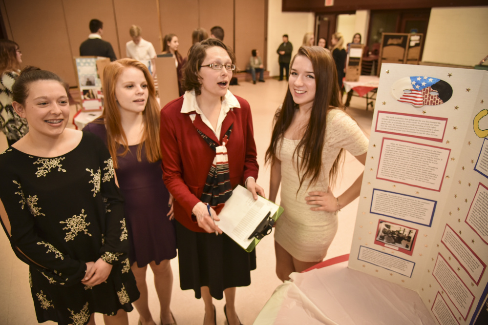 Monmouth Academy sophomores, left to right, Elizabeth Mason, Valerie Fullerton, social studies teacher Jocelyn Gray and student Mckenzie Stevens discuss the team's choice of interviewing Cold War-era veteran Richard Howard. The team created a poster including the history of the Cold War and interview details on what it was like to serve during this period in American history after World War II.