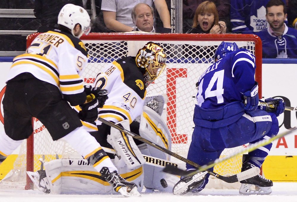 Maple Leafs defenseman Morgan Rielly scores on Tuukka Rask as Bruins center Ryan Spooner defends in the first period.