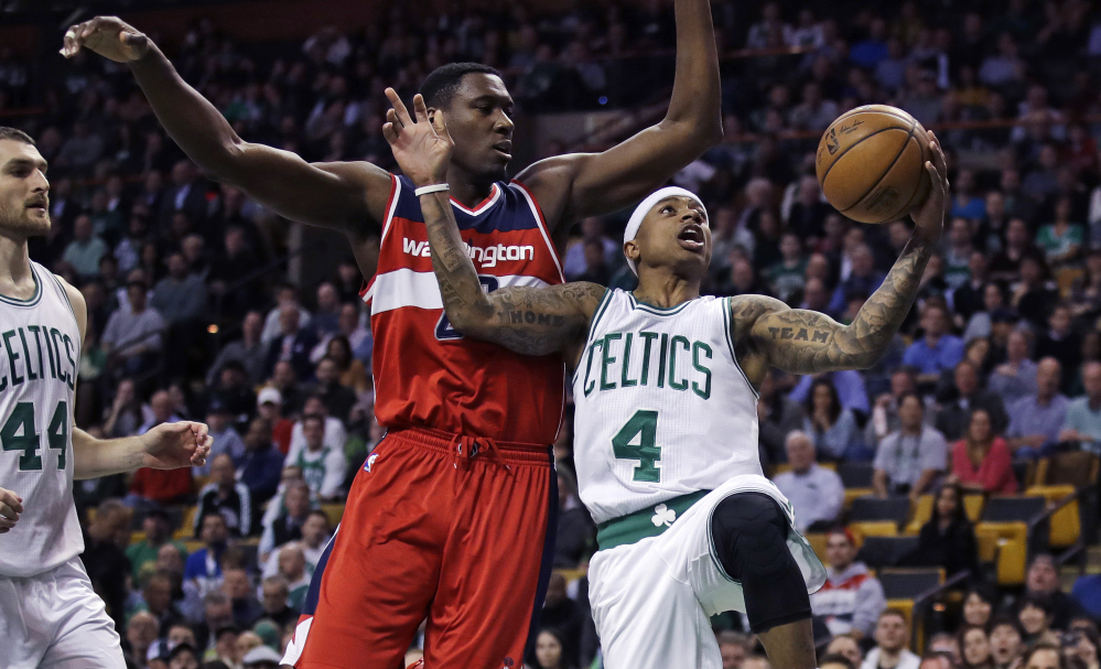 Boston's Isaiah Thomas, right, avoids the defense of Washington's Ian Mahinmi as he drives to the basket curing the Celtics' 110-102 win Monday at Boston. Thomas had 25 points in his return after missing two games with a knee injury.