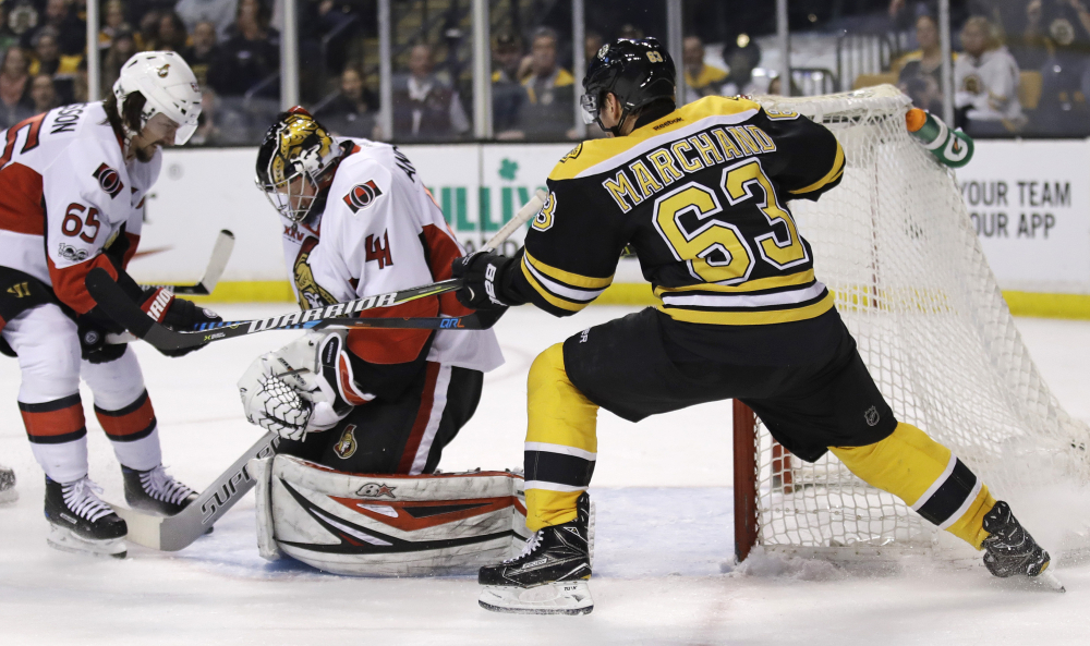 Boston Bruins left wing Brad Marchand tries to break the puck away from Ottawa Senators goalie Craig Anderson on a save during the second period Tuesday. At left is Ottawa Senators defenseman Erik Karlsson.