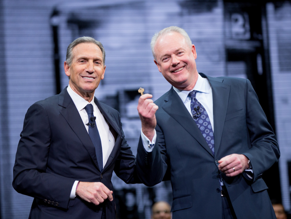 Howard Schultz, Starbucks chairman, left, gives incoming CEO Kevin Johnson the key to the original Pike Place Market store Wednesday during the shareholders meeting in Seattle.