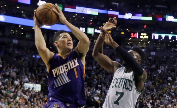 Suns guard Devin Booker, left, goes up for a shot while being defended by Celtics forward Jaylen Brown during the Celtics' 130-120 win Friday in Boston. Booker scores 70 points.