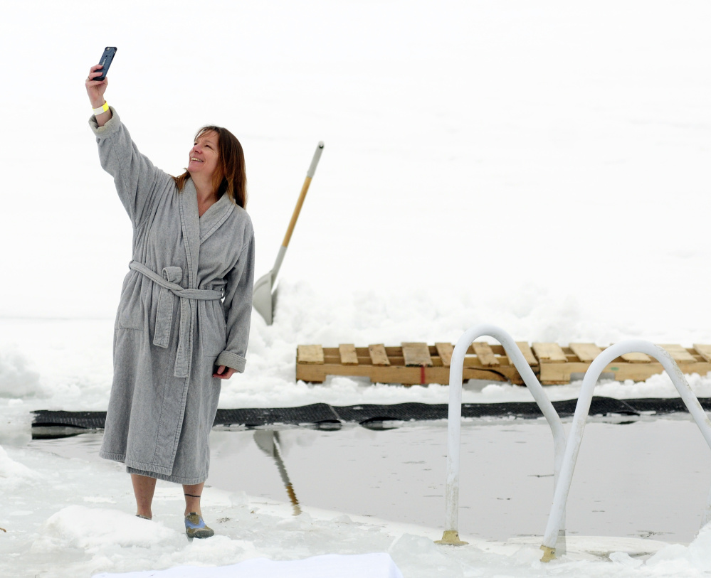 Rhonda Ziehl of Foster, R.I., takes a selfie next to a hole in the Maranacook Lake ice before the Maine Law Enforcement Torch Run Ice Out Plunge on Saturday at Winthrop's town beach.