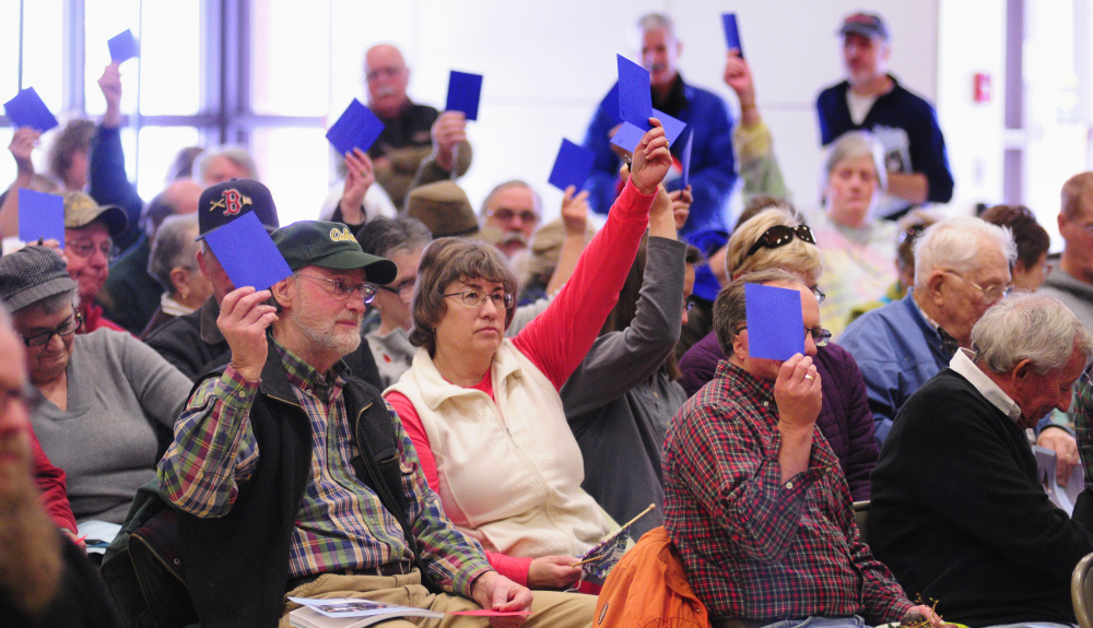 Residents hold up blue cards to vote "yes" on a warrant item Saturday during the China Town Meeting in the China Middle School gymnasium.