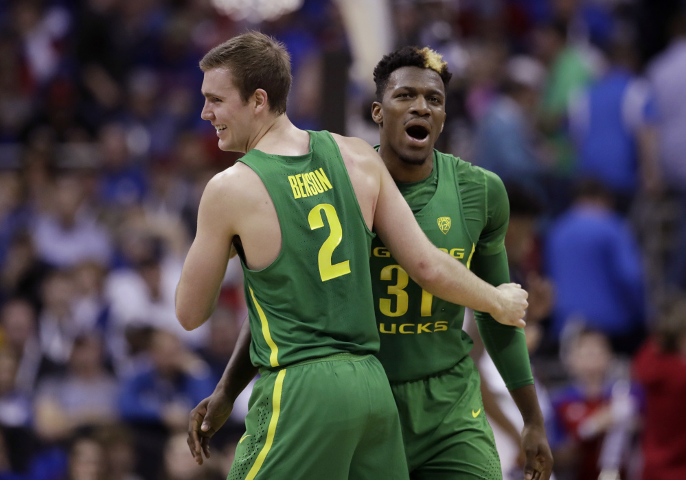 Casey Benson, left, celebrates with teammate Dylan Ennis during Oregon's 74-60 win over Kansas in the Midwest Region final Saturday night in Kansas City, Mo.