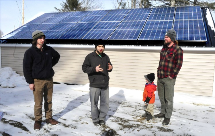 From left, Insource Renewables worker Ben Holt; Joas Hochstetler, manager of Backyard Buildings; and Matt Wagner, project manager for Insource, with his son, Ansel. Backyard Buildings makes solar-power sheds with Maine-based materials.
