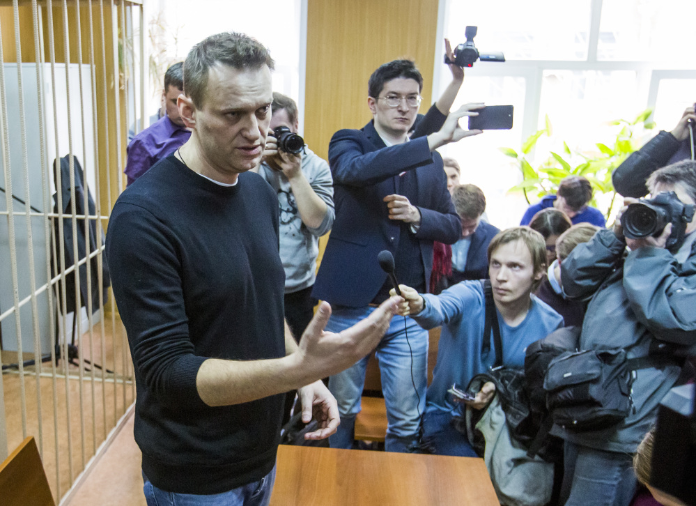 Russian opposition leader Alexei Navalny, foreground, speaks to the press in a courtroom in Moscow on Monday, a day after being arrested while on his way to a major opposition rally. A Moscow court handed a 15-day jail term to Navalny, the protest organizer.