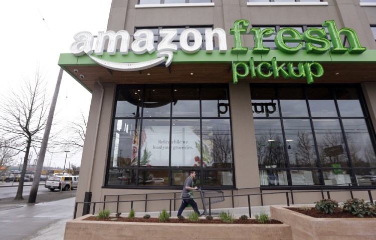 A worker returns a cart after loading groceries ordered online into a customer's car at an AmazonFresh Pickup location Tuesday in Seattle. Amazon is currently beta testing the free service with employees.