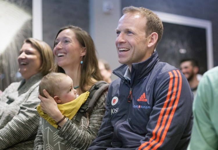 Lowell Bailey watches a recap of the biathlon world championships at Tuesday's press conference at the Press Hotel in Portland with his wife, Erika, and daughter, Ophelia.