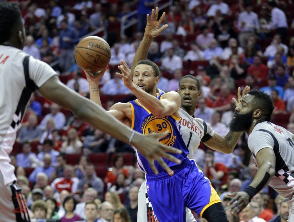 The Warriors' Stephen Curry dishes the ball between Houston Rockets' Clint Capela, Trevor Ariza and James Harden in the first half of Golden State's 113-106 win at Houston. Curry scored 32 points.