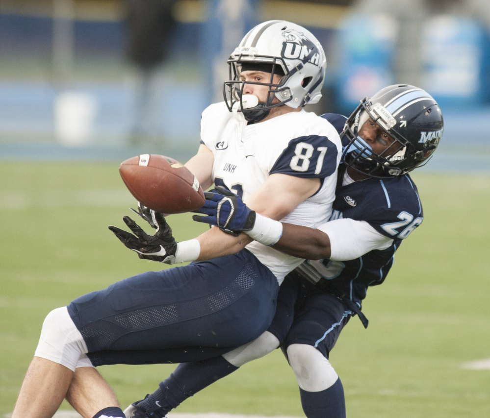 UMaine's Manny Patterson, right, grapples for the ball as he brings New Hampshire receiver Rory Donovan to the ground on Nov. 19 in Orono. UNH won the game, 24-21. (Kevin Bennett photo)