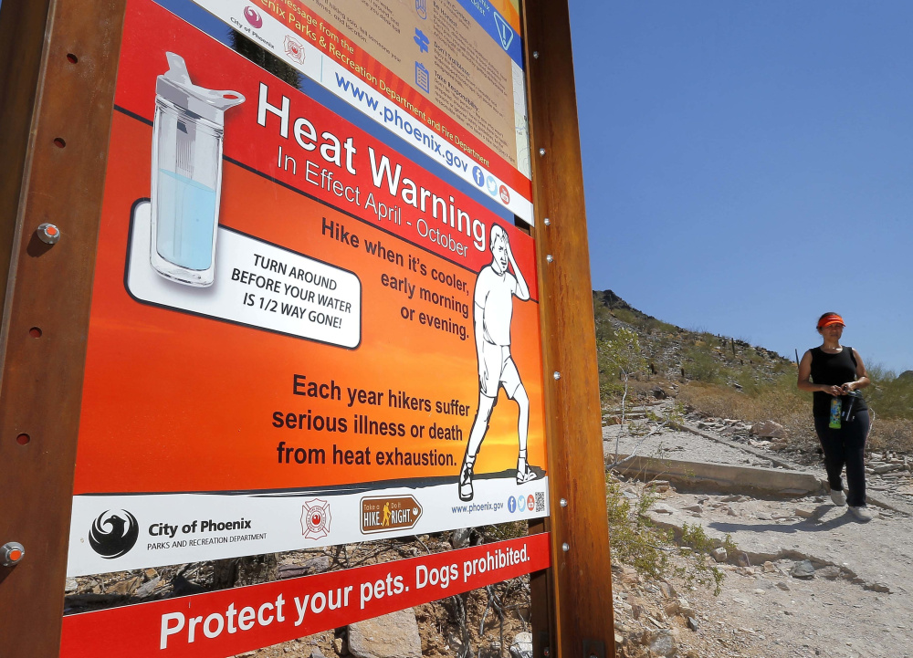 A sign warning of extreme heat is seen on a trailhead at Piestewa Peak in Phoenix, Ariz., in 2016. Phoenix is one of many U.S. cities facing what seems to be the inevitable reality of a hotter and drier future. Public health and economic prosperity are both at risk